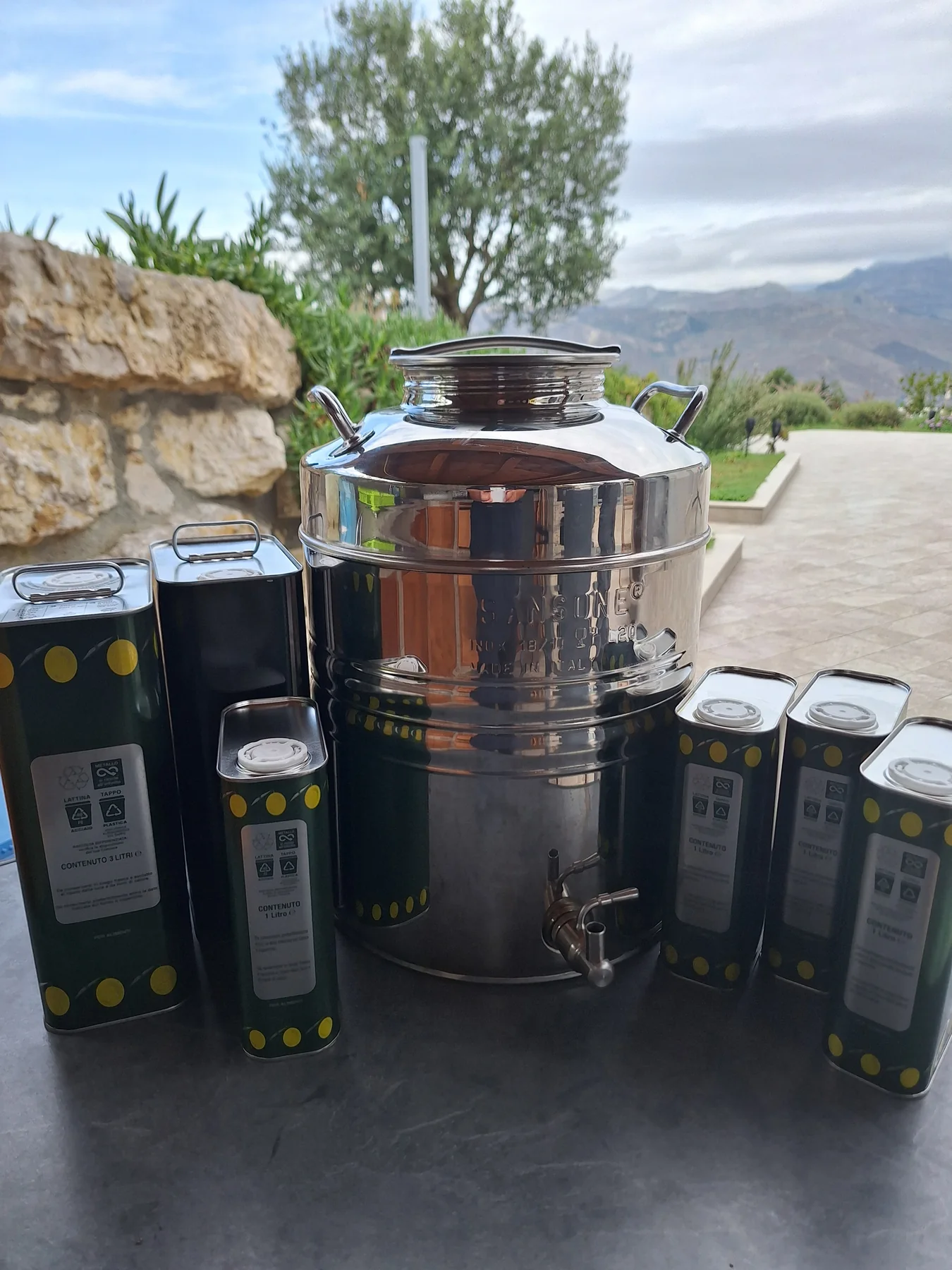Edelstahlbehälter, dunkle Ölkanister und eine Flasche auf einer Terrasse